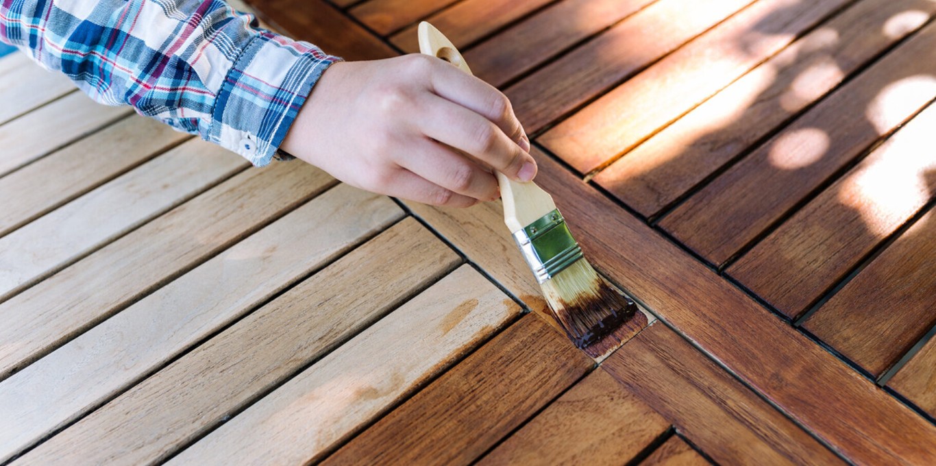 Hand applying protective stain to deck boards